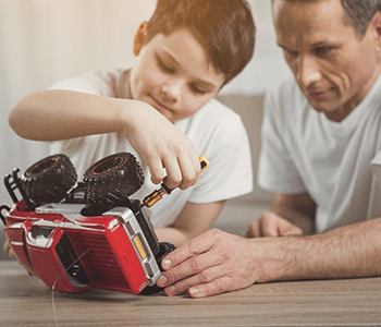 enfant r&eacute;pare son jouet avec son p&egrave;re