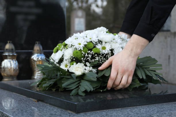 Femme déposant une couronne de fleurs funéraires