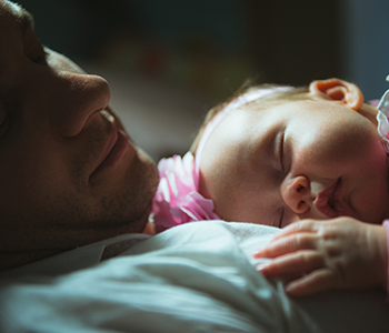 bébé qui dort avec son père - Assurance scolaire et extra-scolaire