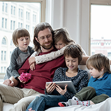 Papa sur un canapé entouré de ses enfants avec une tablette