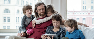 Papa sur un canapé entouré de ses enfants avec une tablette