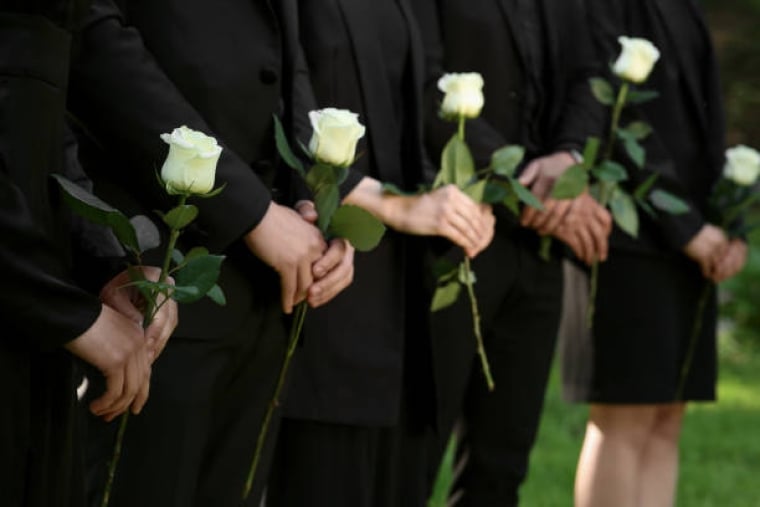 Des gens en vêtements noirs avec des fleurs roses blanches