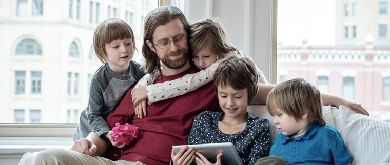 Papa sur un canapé entouré de ses enfants avec une tablette